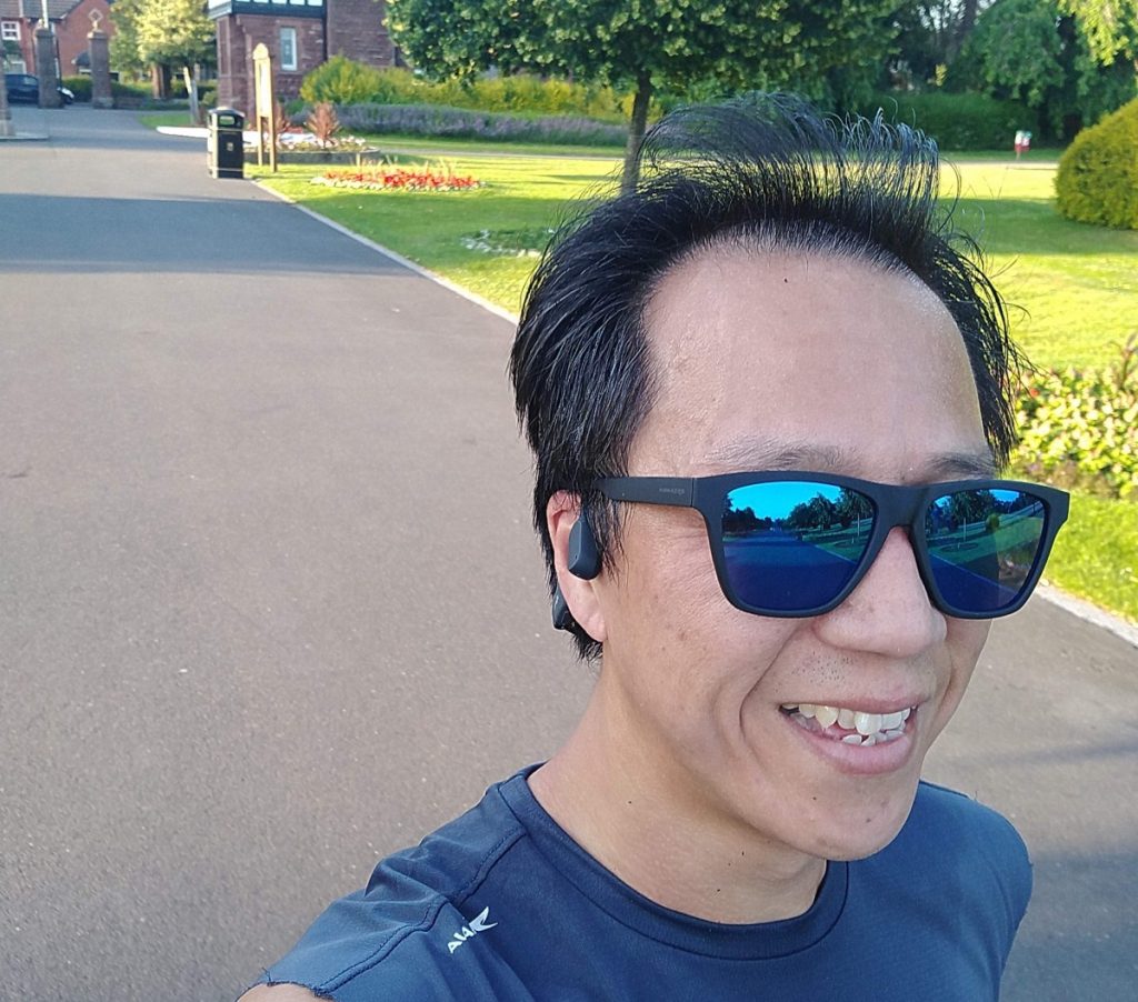 Running through park wearhing Aftershokz Aeropex and sunglasses